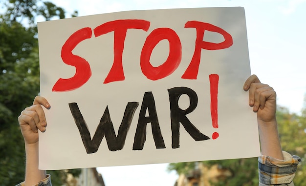 Woman holding poster with words stop war outdoors closeup