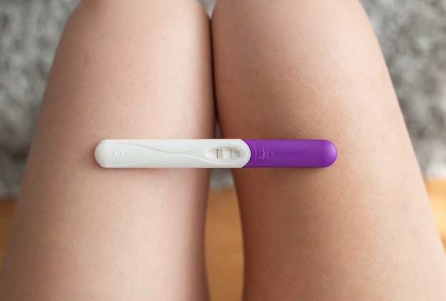 Photo woman holding a pregnancy test on her knees