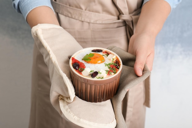 Woman holding ramekin with baked egg