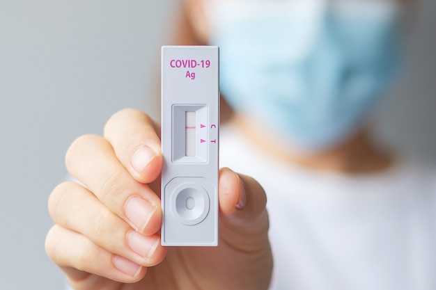 Woman holding rapid antigen test kit with negative result during swab covid-19 testing. coronavirus self nasal or home test, lockdown and home isolation concept