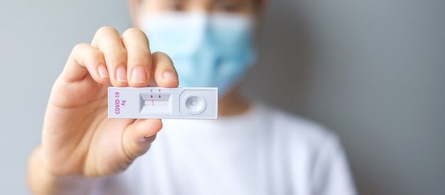 Woman holding Rapid Antigen Test kit with Negative result during swab COVID-19 testing. Coronavirus Self nasal or Home test, Lockdown and Home Isolation concept