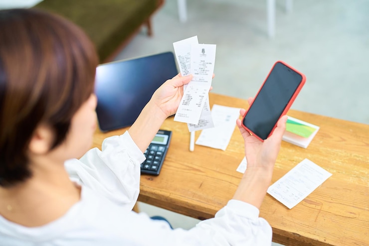 Photo a woman holding a receipt and smartphone indoors