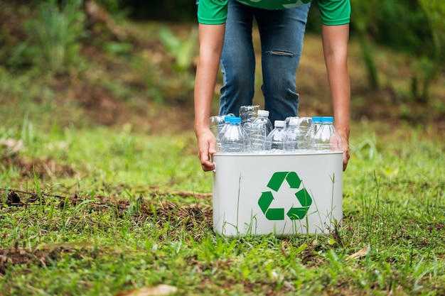 a woman holding a recycle bin with plastic bottles in the outdoors