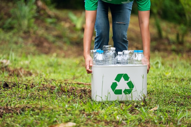 A woman holding a recycle bin with plastic bottles in the outdoors