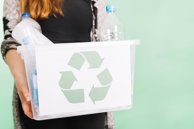 Photo woman holding recycle crate for recycling against pastel background