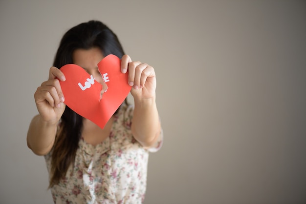 Woman holding red broken heart with love text. valentines day concept