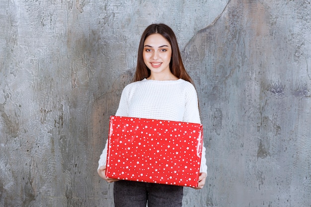 woman holding a red gift box with white dots on it.