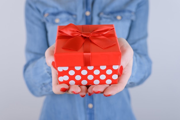 Woman holding red giftbox on isolated gray background