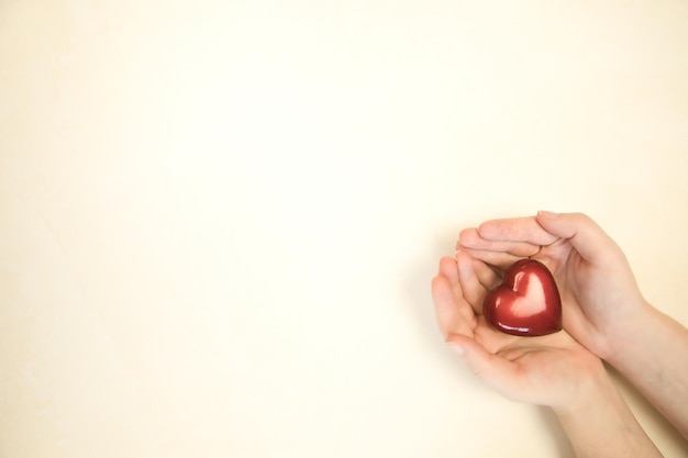 Woman holding red heart in hands on bright color background top view copy space love