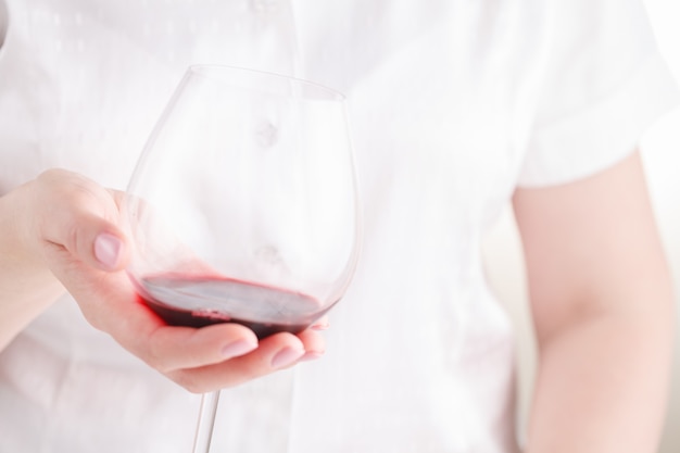 レストランで赤ワインのガラスを保持している女性