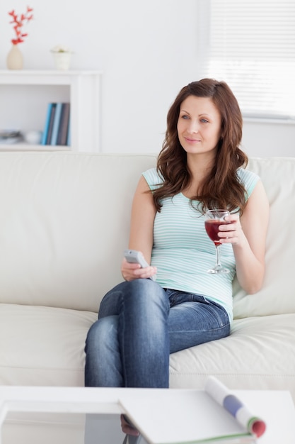 Woman holding a remote control and a glass of wine