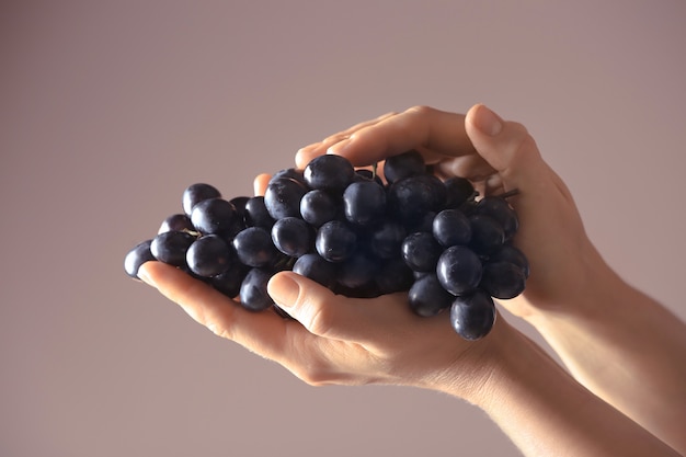 Woman holding ripe sweet grapes on color