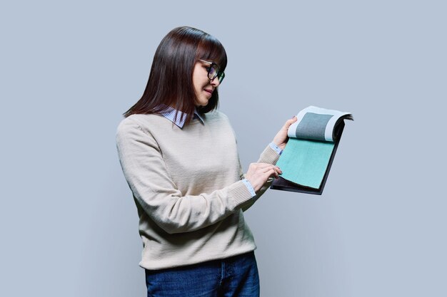 Photo woman holding samples of fabrics for interior on grey background