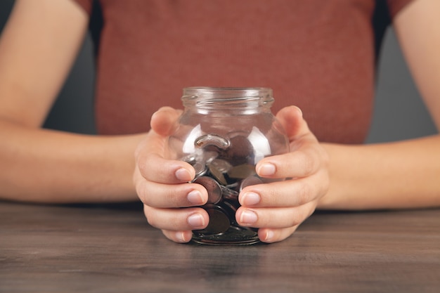 Woman holding savings jar by the table