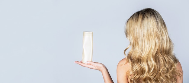 Bottiglia di shampoo della holding della donna. bella ragazza bionda con una bottiglia di shampoo in mano.