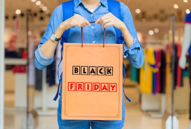 黒の金曜日の概念とショッピングモールでショッピングバッグを持っている女性。