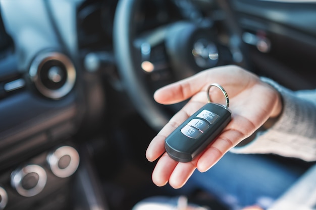 a woman holding and showing car key while sitting in the car