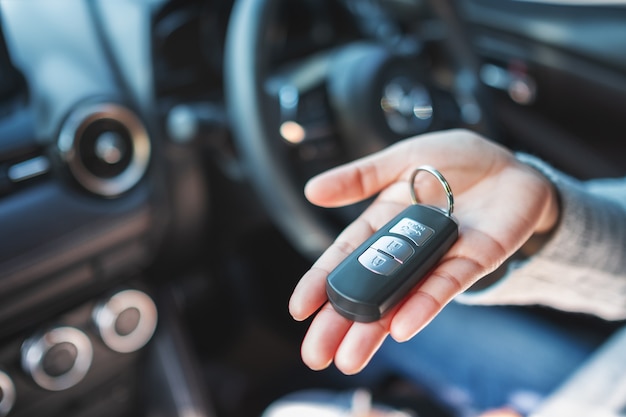 Photo a woman holding and showing car key while sitting in the car