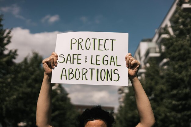 Photo woman holding a sign with a phrase protect safe and legal abortions