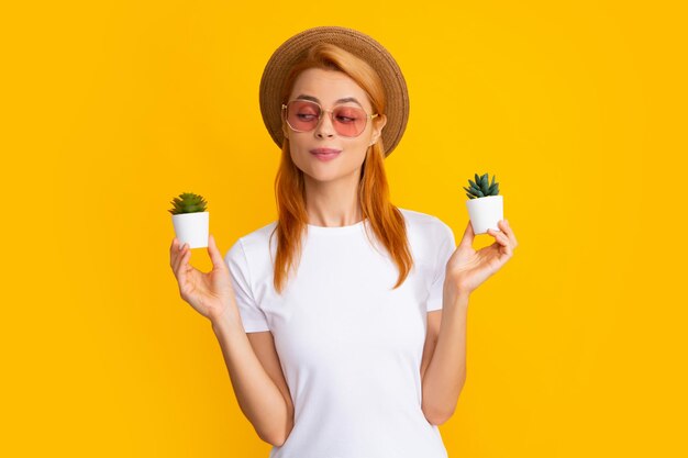 Woman holding a small cactus in hands gently on yellow background