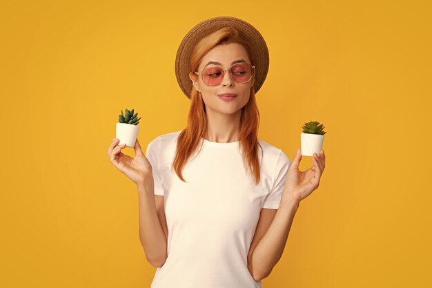 Woman holding a small cactus in hands gently on yellow background