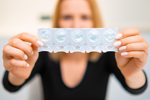 Woman holding a small tray with disposal contact lenses in front of yourself