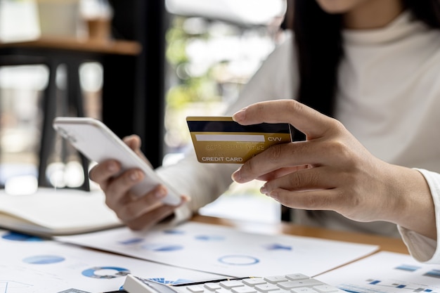 A woman holding a smartphone and a credit card, she is doing online shopping through a smartphone app by paying credit card payments. Online shopping ideas with a credit card.