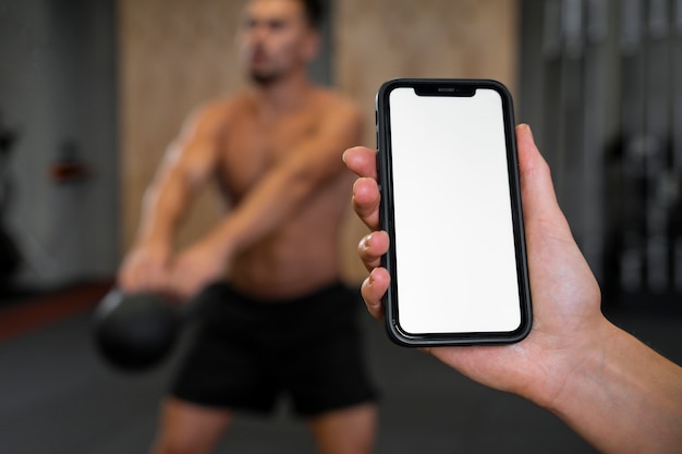 Photo woman holding smartphone in hand while working out indoors