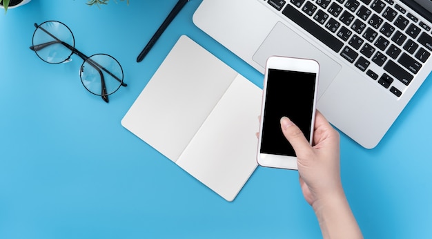 Woman holding a smartphone over office desk