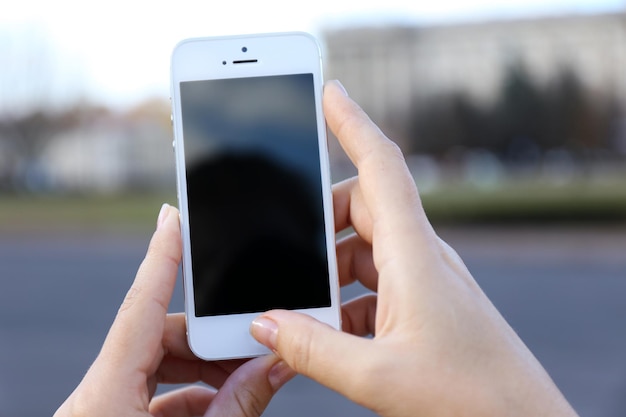 Woman holding smartphone outside