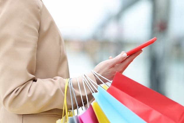 Woman holding smartphone and packages in her hand