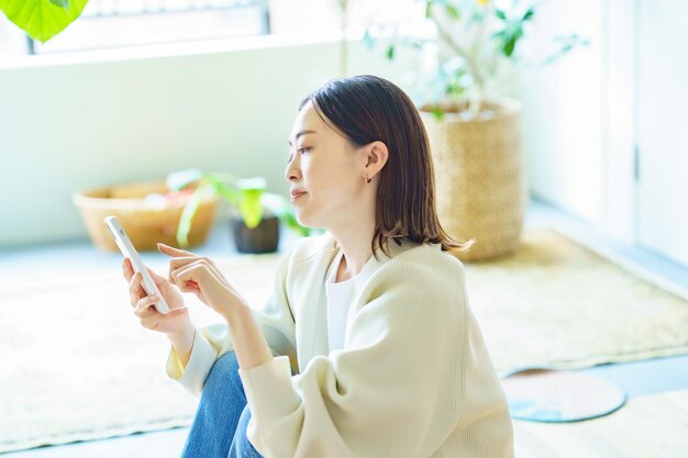 部屋でスマートフォンを持っている女性