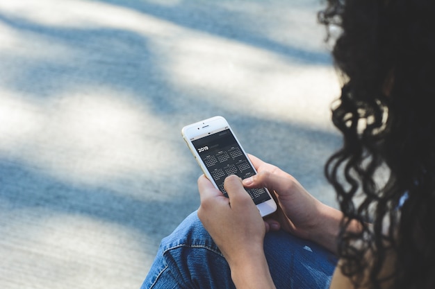 Smartphone della tenuta della donna con l'app del calendario