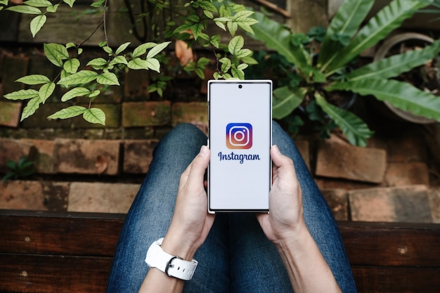 Женщина держит смартфон с приложением Instagram на экране. Instagram - приложение для обмена фотографиями для смартфонов.