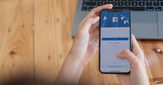 Woman holding a Smartphone with social Internet service Facebook on the screen.