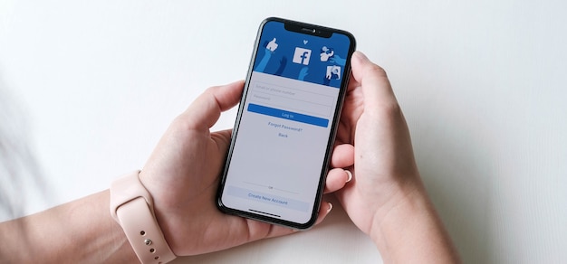 Woman holding a smartphone with social Internet service Facebook on the screen.