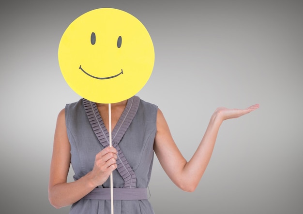 Woman holding a smiley face over her face