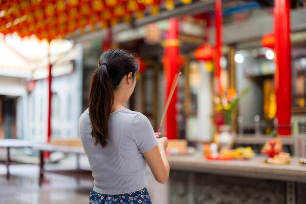 Woman holding smoking incense sticks in chinese temple