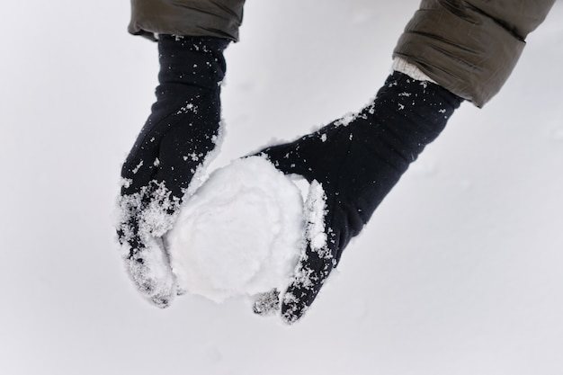 Woman holding snowball in her hands 