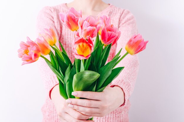 ピンクのチューリップの春の花束を手に持っている女性。