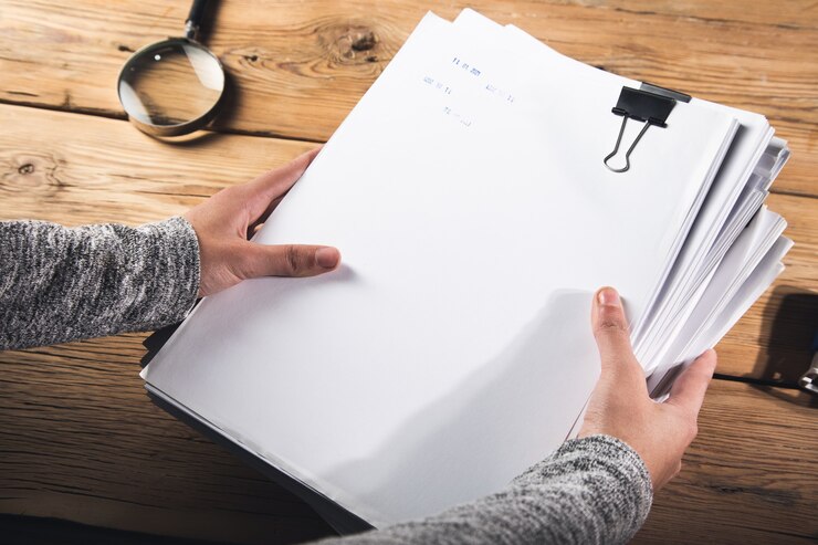 Photo woman holding stack of files with magnifier on the table