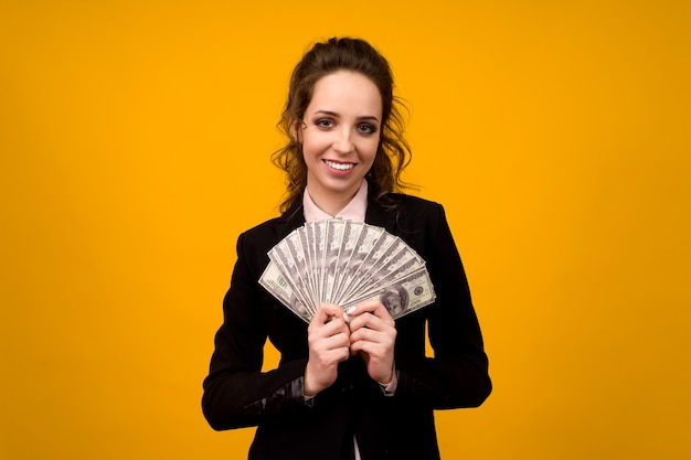 Woman holding stack of money isolated on yellow background