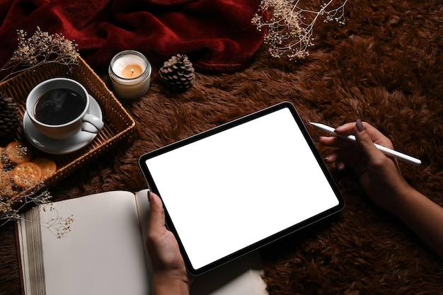 Woman holding stylus pen and using digital tablet on brown carpet