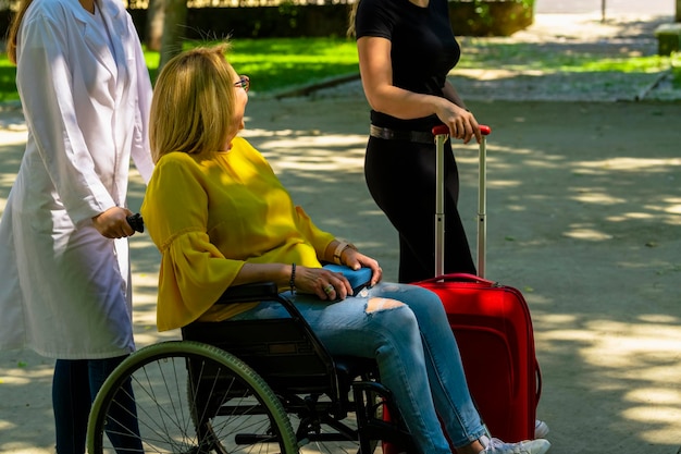 Foto donna che tiene una valigia mentre il dottore spinge il paziente sulla sedia a rotelle