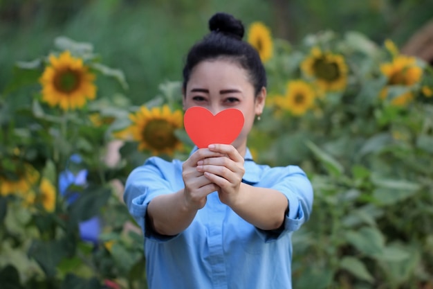 彼女の顔の前に愛のシンボルを保持している女性