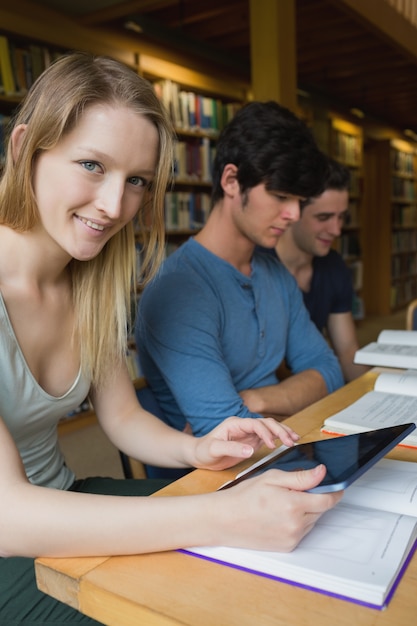 Foto donna che tiene un tablet pc seduto alla libreria