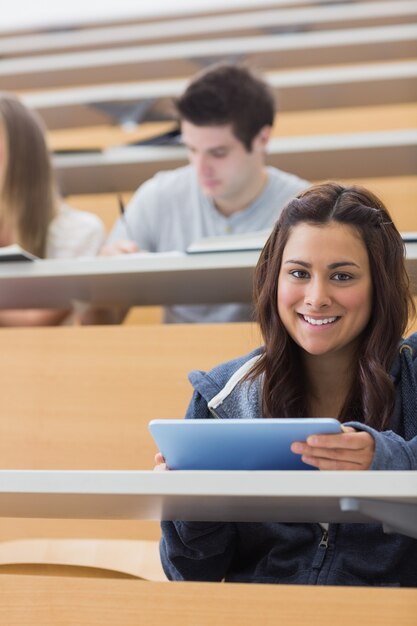 Woman holding a tablet pc while smiling in lecture hall