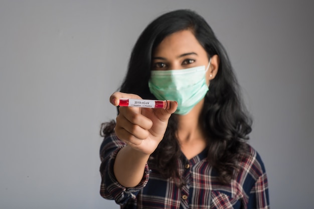 Woman holding a test tube with blood sample for coronavirus or 2019-nCoV analyzing.