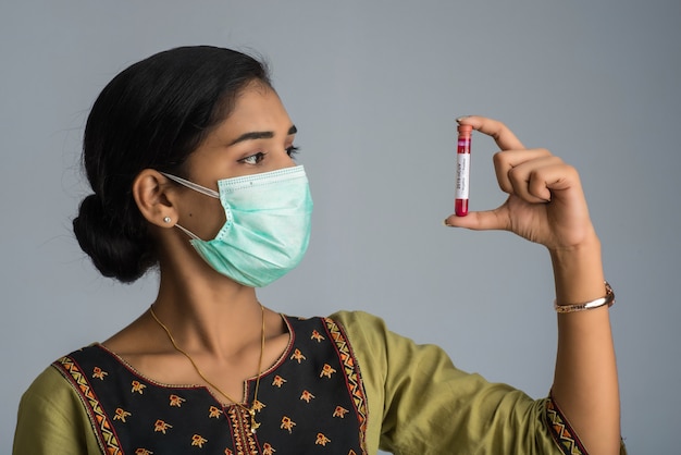 Woman holding a test tube with blood sample for coronavirus or 2019-nCoV analyzing.