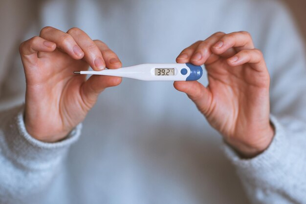 Woman holding thermometer with high temperature closeup